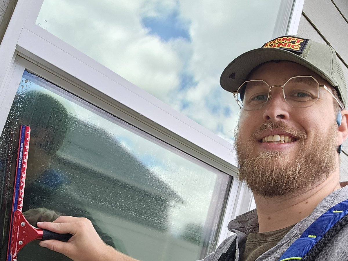 Clear Shine tech cleaning exterior windows with a squeegee